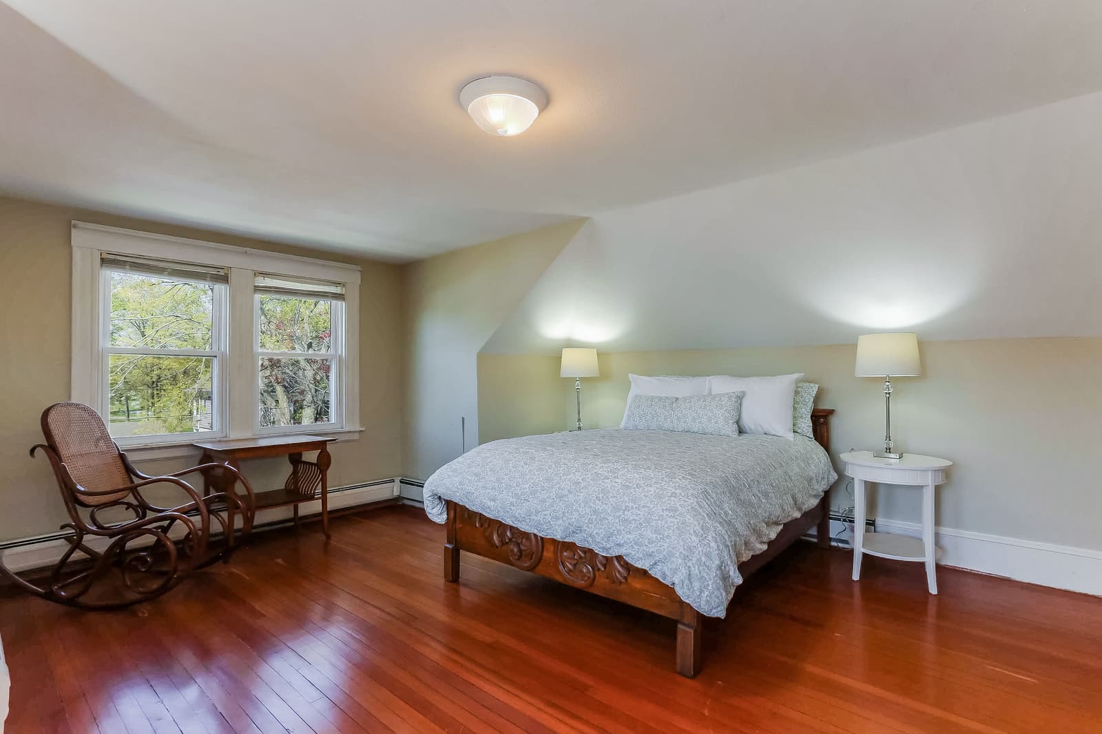 Bedroom with a rocking chair, a bed, and two windows in the third-floor apartment on Grennan Rd.
